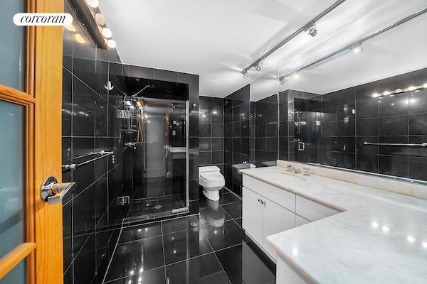 full bath featuring tile walls, toilet, a stall shower, vanity, and tile patterned floors