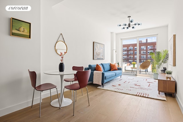 sitting room featuring baseboards, wood finished floors, visible vents, and an inviting chandelier