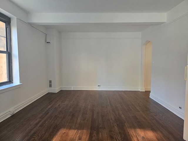 unfurnished room featuring dark hardwood / wood-style flooring and beam ceiling