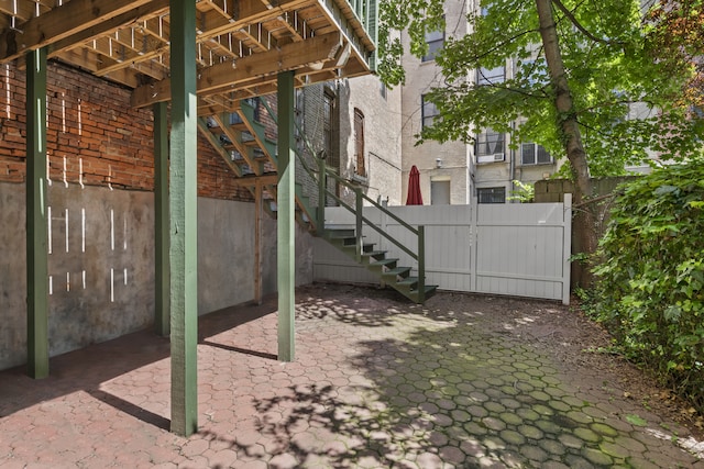 view of patio featuring fence and stairway