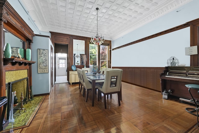 dining area with crown molding, wainscoting, a fireplace, an ornate ceiling, and wood walls