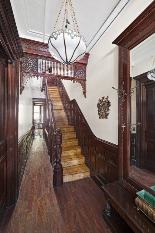 staircase with wood finished floors and wainscoting