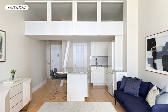 interior space with baseboards, light wood-style floors, visible vents, and a sink