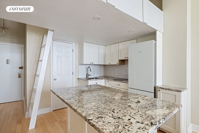 kitchen with visible vents, decorative backsplash, freestanding refrigerator, white cabinets, and a sink