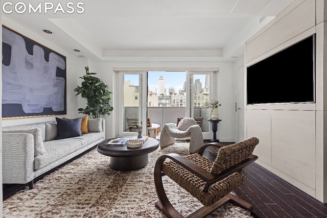 living room featuring wood-type flooring and a tray ceiling