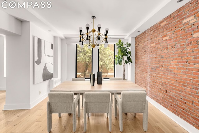 dining space featuring a notable chandelier, light wood-type flooring, and brick wall