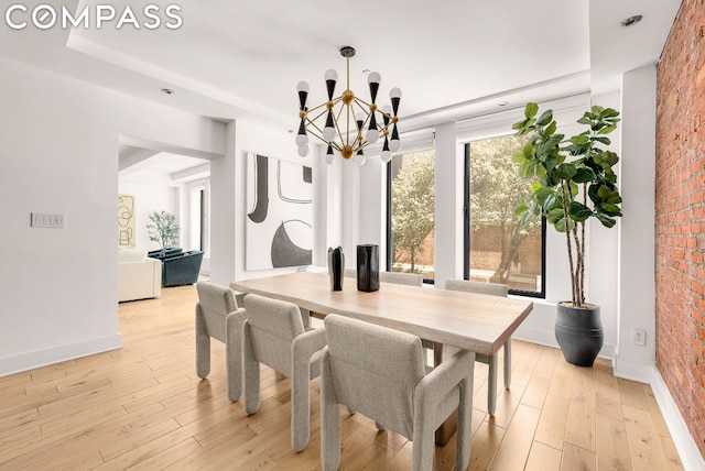 dining space featuring a chandelier, brick wall, and light hardwood / wood-style floors