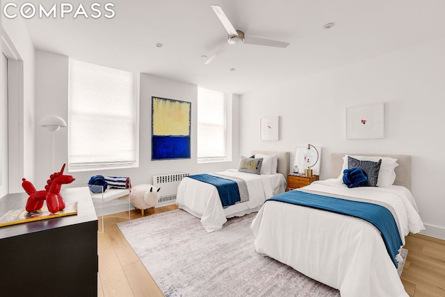 bedroom with ceiling fan, radiator heating unit, and light hardwood / wood-style floors