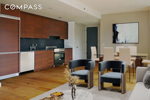 kitchen featuring sink, decorative backsplash, light hardwood / wood-style floors, and appliances with stainless steel finishes