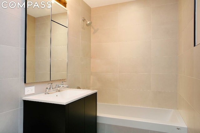 bathroom with vanity, tile walls, and tiled shower / bath