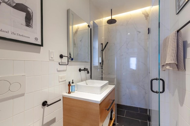 bathroom featuring a shower with door, vanity, and tile walls