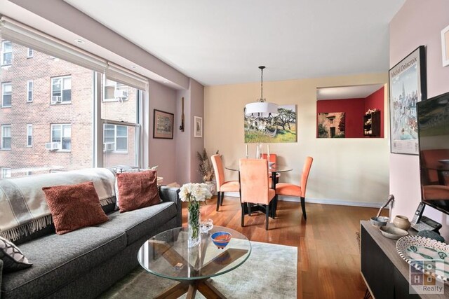 living room featuring cooling unit, wood finished floors, and baseboards