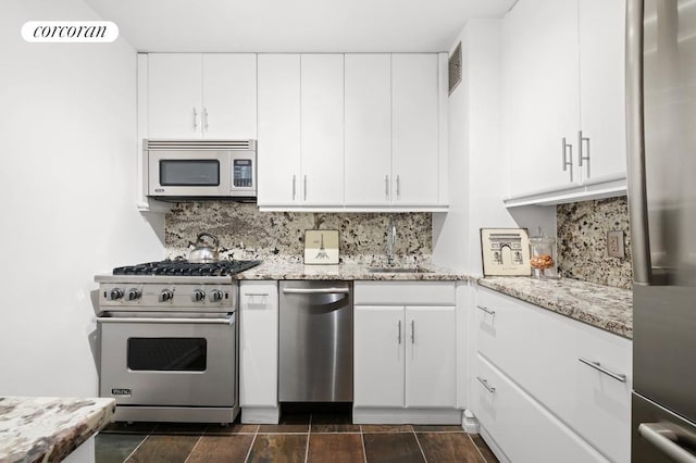 kitchen with light stone counters, stainless steel appliances, white cabinets, and tasteful backsplash