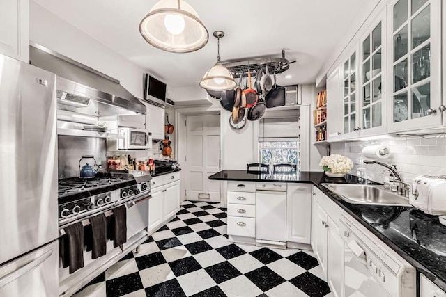 kitchen with dark countertops, tile patterned floors, a peninsula, stainless steel appliances, and a sink