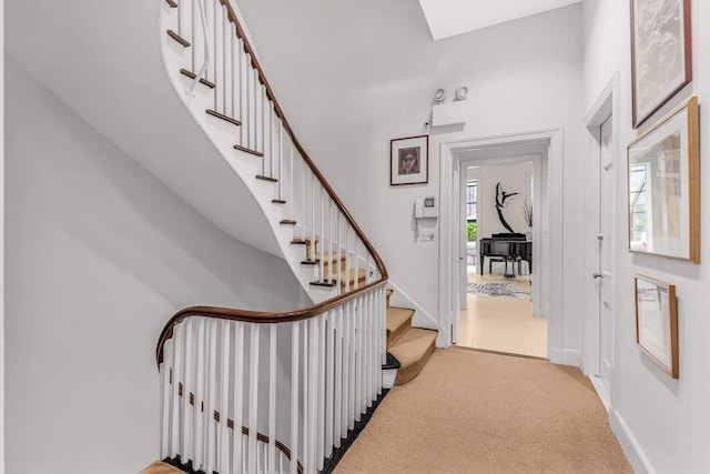 foyer featuring light carpet, a high ceiling, stairs, and baseboards