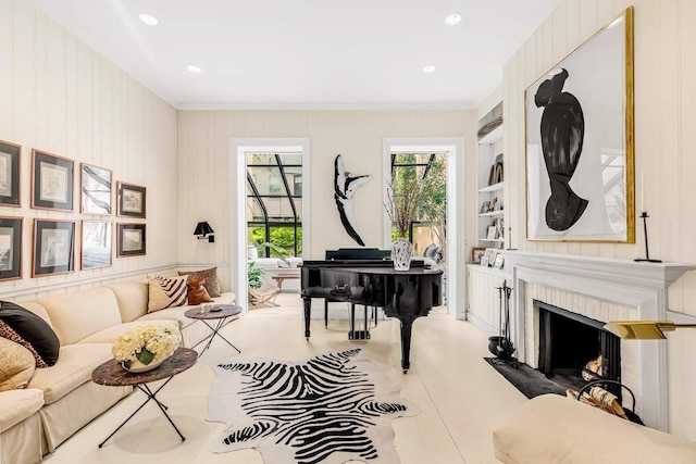 sitting room with a fireplace with flush hearth, ornamental molding, and built in shelves