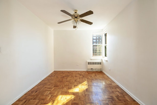 empty room featuring ceiling fan, radiator, and light parquet flooring