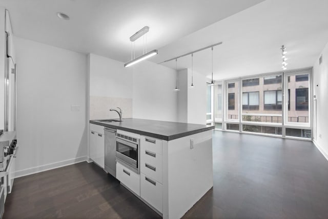 kitchen featuring sink, white cabinetry, decorative light fixtures, kitchen peninsula, and stainless steel appliances