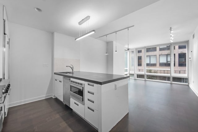 261 W 28th St Unit 2D, New York City, NY 10001 - kitchen with dark countertops, a peninsula, appliances with stainless steel finishes, dark wood-type flooring, and expansive windows