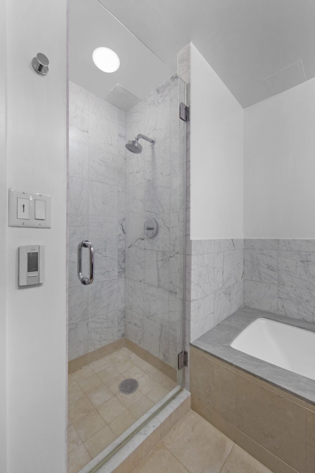 bathroom featuring a stall shower, tile patterned flooring, and a bath