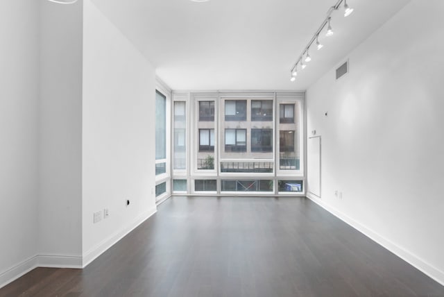 unfurnished room featuring dark wood-style floors, rail lighting, visible vents, and baseboards