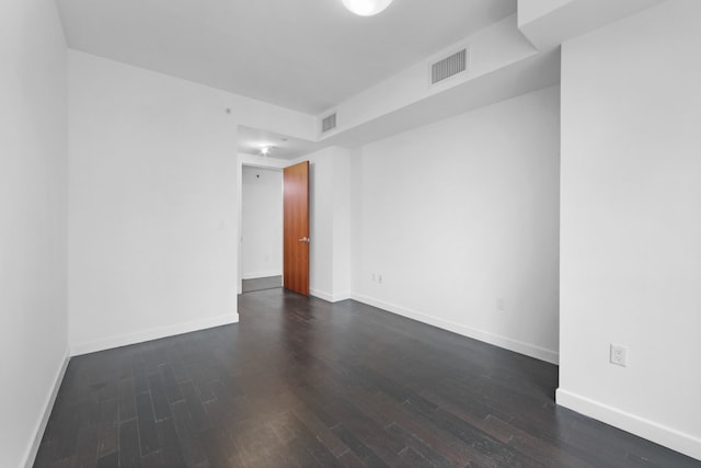 unfurnished room featuring baseboards, visible vents, and dark wood-type flooring