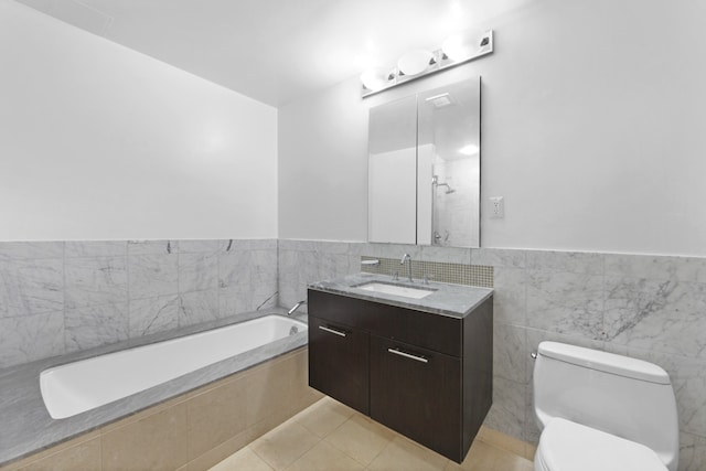 bathroom featuring a garden tub, toilet, vanity, tile walls, and tile patterned floors