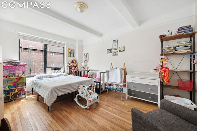 bedroom featuring light hardwood / wood-style floors and beamed ceiling