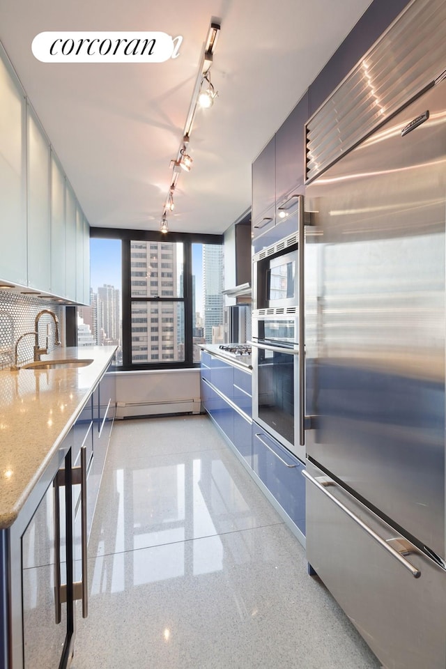 kitchen featuring light speckled floor, a city view, baseboard heating, stainless steel built in fridge, and a sink