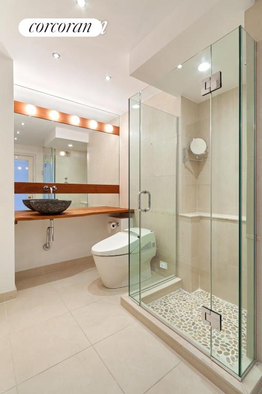 bathroom featuring a shower with door, vanity, tile patterned floors, and toilet