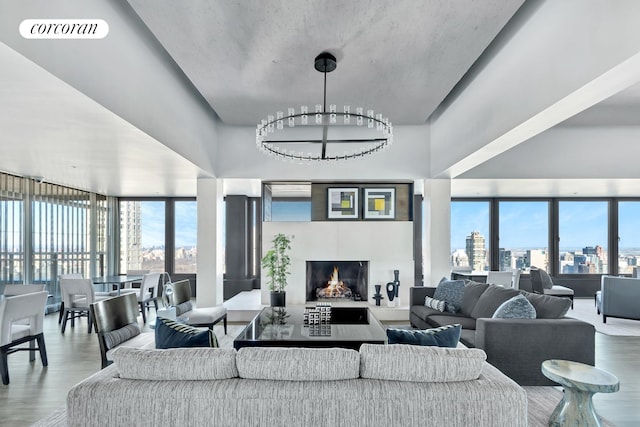 living area with visible vents, a warm lit fireplace, a view of city, and wood finished floors