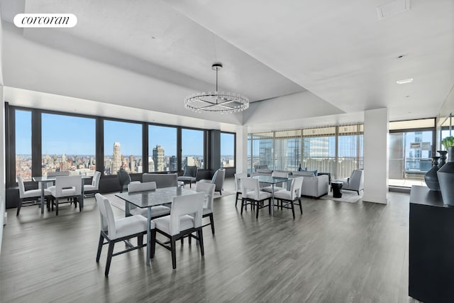 dining room with a view of city, wood finished floors, visible vents, and a healthy amount of sunlight