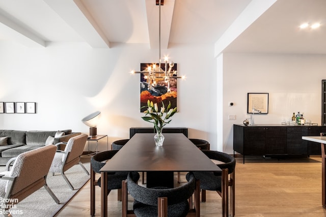 dining room featuring a notable chandelier, beam ceiling, light hardwood / wood-style floors, and bar area