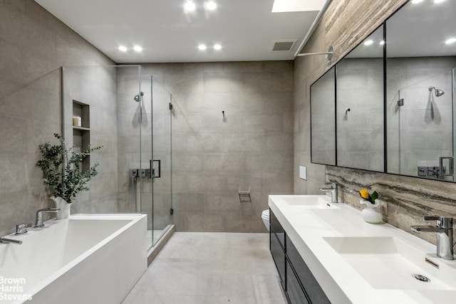 full bathroom featuring tile walls, vanity, and shower with separate bathtub