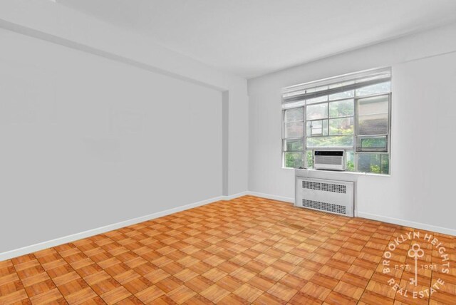 unfurnished room featuring baseboards, cooling unit, and radiator