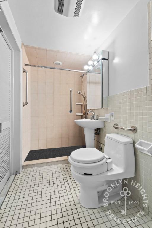 bathroom featuring a stall shower, visible vents, toilet, tile patterned floors, and tile walls