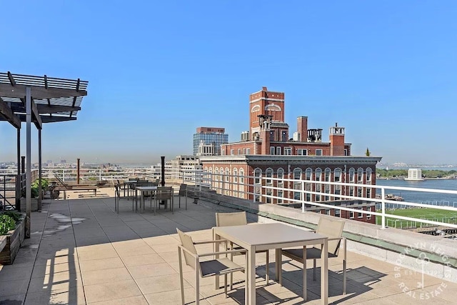 view of patio / terrace featuring outdoor dining area, a pergola, a water view, and a city view