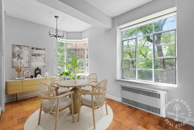 dining space featuring baseboards, radiator heating unit, and a notable chandelier