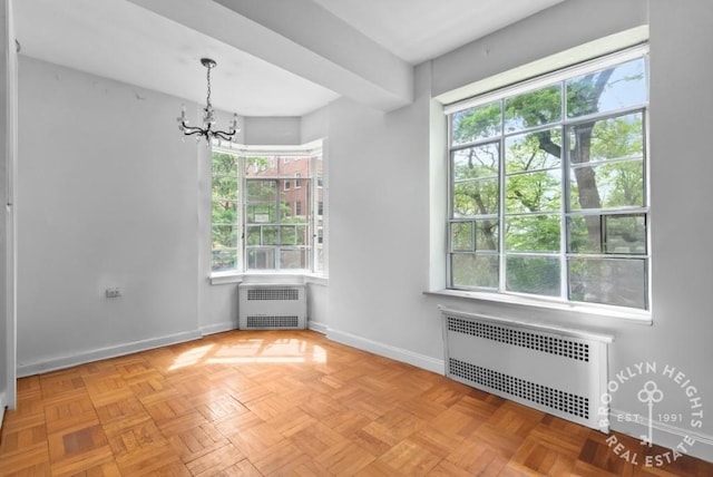 spare room featuring a notable chandelier, radiator, and baseboards