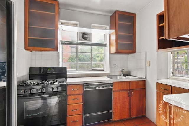 kitchen with light countertops, decorative backsplash, a sink, and black appliances