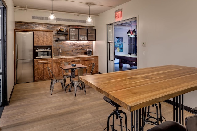 dining space with visible vents, wet bar, and light wood-style floors