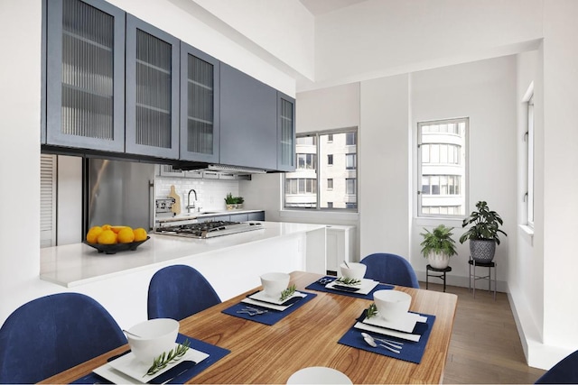 kitchen with glass insert cabinets, dark wood-type flooring, light countertops, fridge, and stainless steel gas stovetop