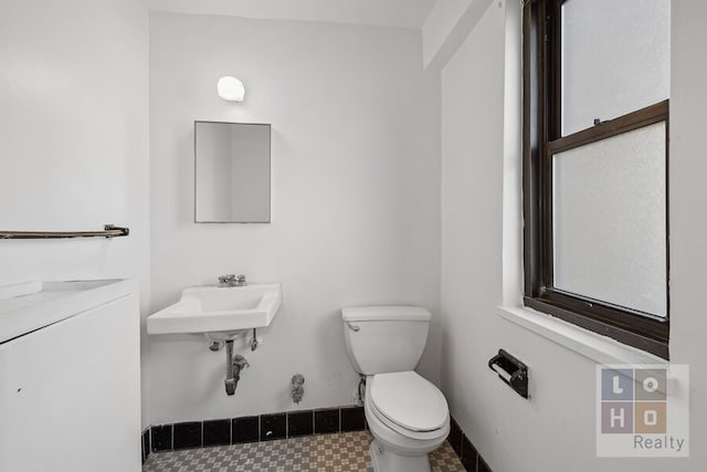 bathroom with toilet, baseboards, and a sink