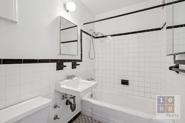 bathroom with shower / bath combination, tile walls, and toilet