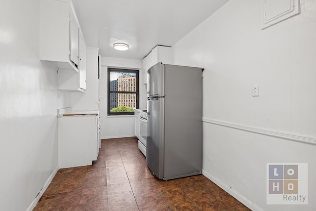 kitchen featuring baseboards, white cabinets, gas range gas stove, and freestanding refrigerator