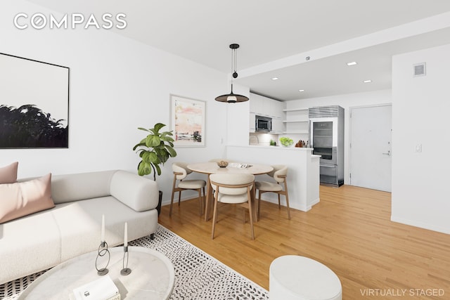 living room featuring light wood-type flooring, visible vents, baseboards, and recessed lighting