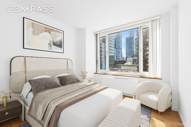 bedroom featuring a view of city, baseboards, and wood finished floors