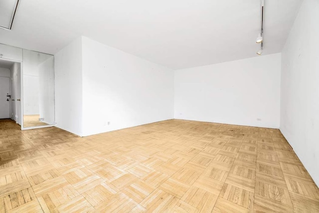 empty room with rail lighting and light parquet flooring