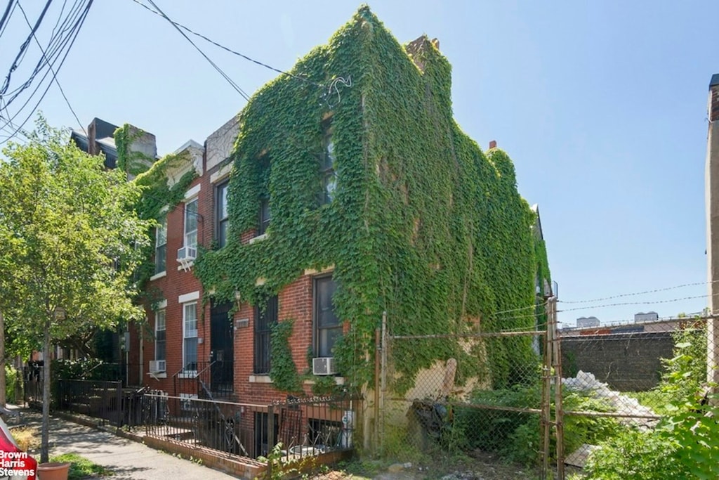 view of side of home with a fenced front yard, cooling unit, and brick siding