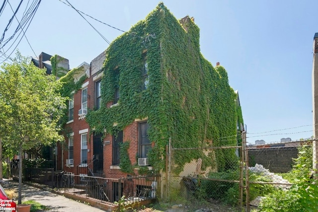 view of side of home with a fenced front yard, cooling unit, and brick siding